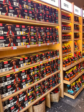 A well-organized display shows various coffee boxes on wooden shelves. The colors are vibrant, with red, yellow, and black packaging. This arrangement highlights coffee products.