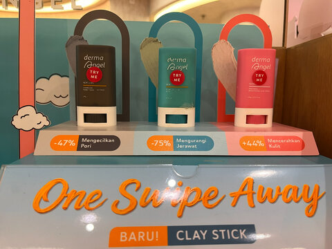 Display of clay stick products in vibrant packaging. Three tubes are arranged prominently with color-coded labels indicating different features. Bright, engaging design promotes skincare.