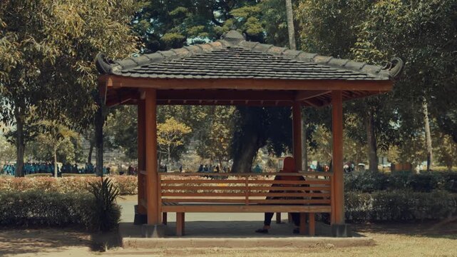 Muslim Woman Sitting Alone in a Traditional Wooden Gazebo