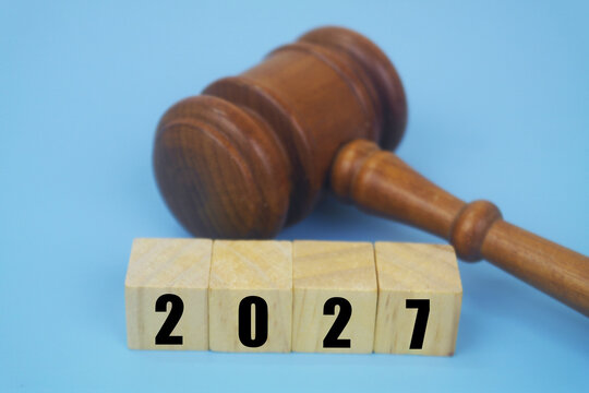 Wooden judge gavel and numbers 2027 on cubes on blue background. Legal system and laws in 2027 concept.	