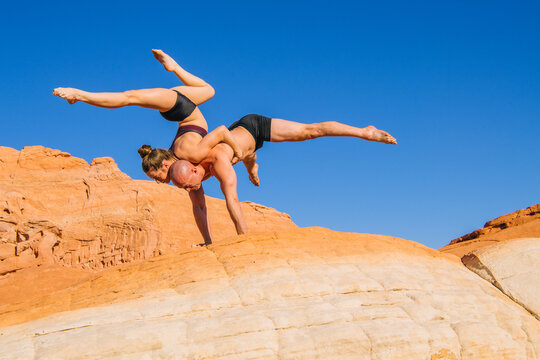Acrobatic yoga balancing on rocky desert landscape