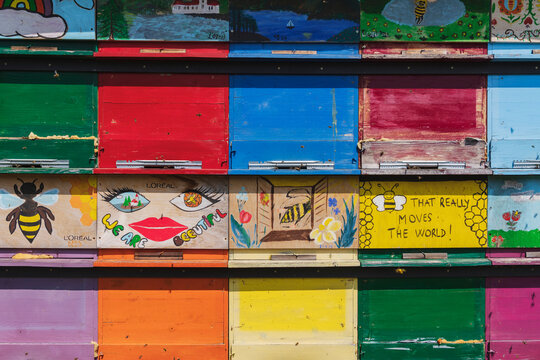 Colorful painted wooden bee hives with bees at an outdoor apiary