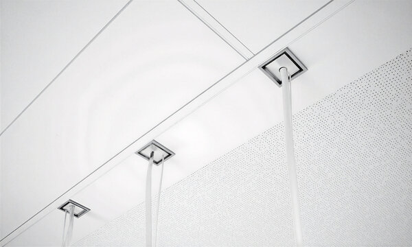 Acoustic ceiling texture white perforated tiles and recessed lighting fixtures hanging from a modern office interior workspace