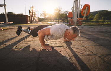 Man with prosthetic leg exercising at sunset