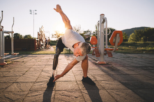 Mature man with a prosthetic leg performing a standing stretching exercise