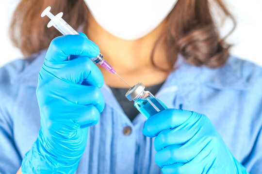 doctor's hand holds a syringe and a blue vaccine bottle at the hospital. Health and medical concepts.	