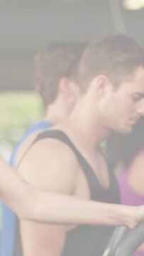 Vertical video: Man in black tank top gripping handles checking console, starting cardio tracking