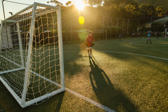 teenage soccer goalie at sunset, with long shadow
