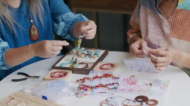 asian people making stringing colorful beads in creative craft workshop