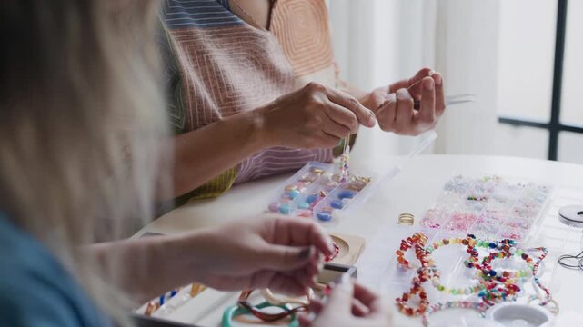 asian people making stringing colorful beads in creative craft workshop