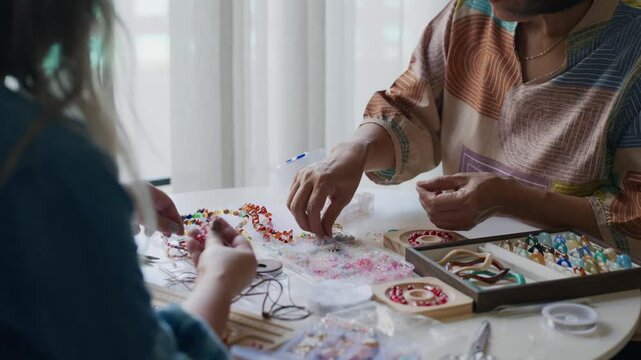 asian people making stringing colorful beads in creative craft workshop
