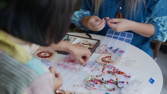 asian people making stringing colorful beads in creative craft workshop