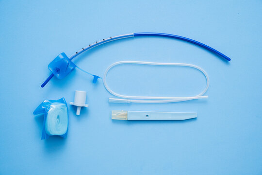 Tracheostomy tube medical kit with surgical introducer and neck ties on blue background for emergency breathing
