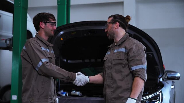 Automotive Mechanics Inspecting Vehicle Undercarriage During Professional Car Repair. Two automotive mechanics inspecting the underside of a vehicle inside a professional repair workshop, represen