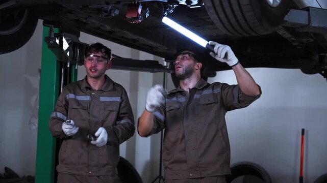 Automotive Technicians Inspecting Vehicle Undercarriage and Mechanical Components. Two automotive technicians inspecting mechanical components underneath a vehicle in a professional repair workshop, r