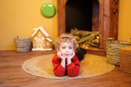 Young boy smiling during Christmas celebration, lying on a rug in a festive home setting, enjoying holiday atmosphere