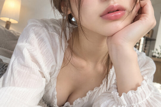 白いフリルの服で頬杖をつく女性の艶のある唇の接写