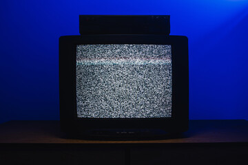Plakat Retro CRT television with VCR displaying analog static interference in dark room with blue lighting