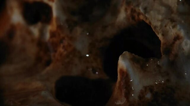 Cinematic rain drops hitting porous ancient bone structure with visible macro raindrops Horizontal Video