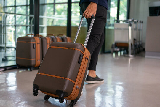 Man Pulling Wheeled Suitcase Through Airport Terminal