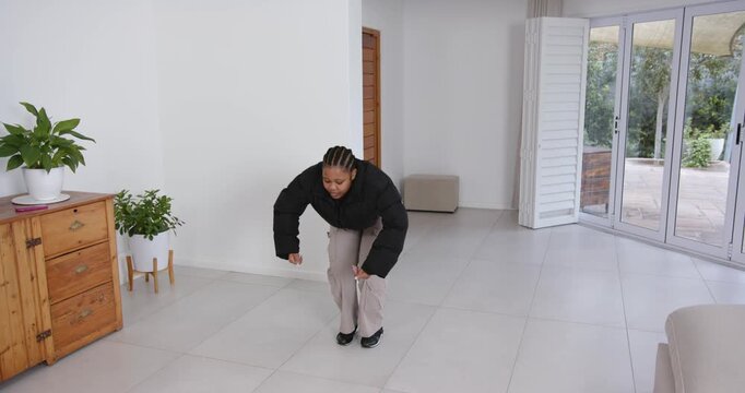 High speed photography for dynamic scenes, woman in black jacket exercising indoors, squatting on ti