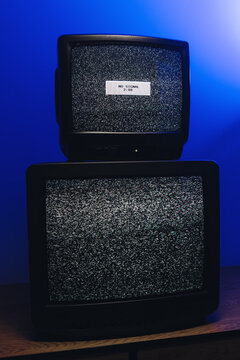 Vintage CRT televisions displaying static noise and no signal under blue lighting