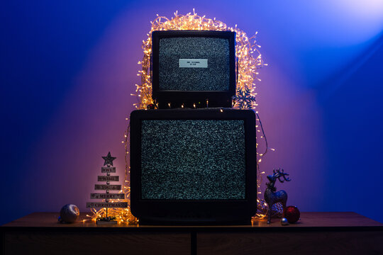 Vintage CRT televisions showing static among glowing holiday lights and decorations