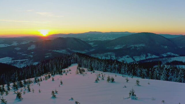 An extraordinary valley with hills and mountains covered with fir forests against the backdrop of a bright fiery sunset