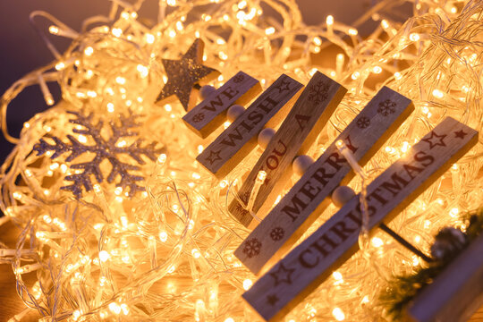 Wooden tree ornament with Merry Christmas message surrounded by glowing warm fairy lights