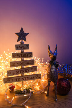 Wooden Christmas tree and glitter reindeer surrounded by warm glowing fairy lights