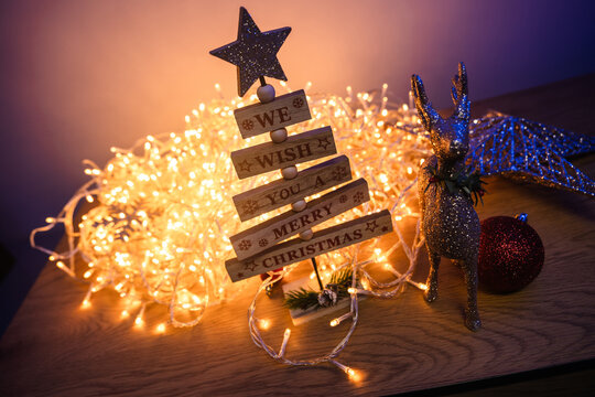 Wooden Christmas tree and glitter reindeer surrounded by warm glowing fairy lights