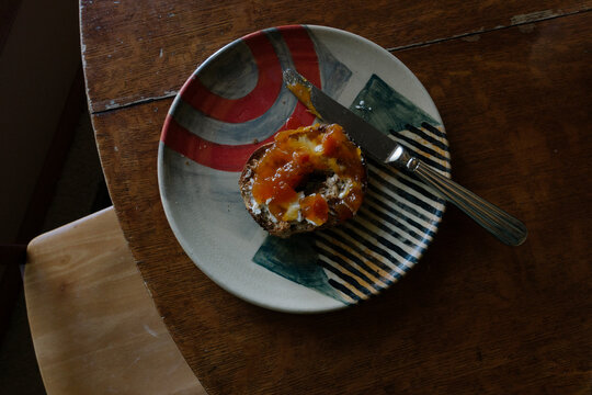 Top view of a sweet pastry with peach jam on a ceramic plate on a wooden table