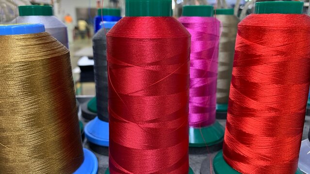 Colorful thread spools arranged in a textile workshop, showcasing materials used for sewing and embroidery applications