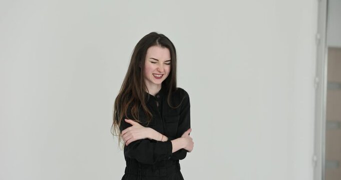 Woman strokes upper arms with hands trying to warm freezing body. Hunched posture of female emphasizes harsh wintry temperature around. Slow motion