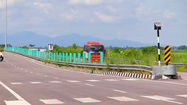 Dibrugarh, Assam, India &ndash; 23 September 2026: A public roadway with a bus, solar-powered roadside lighting, safety barriers, road markings and surrounding green agricultural fields