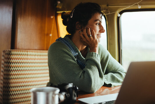 Thoughtful traveler working in a cozy camper van, looking out the window