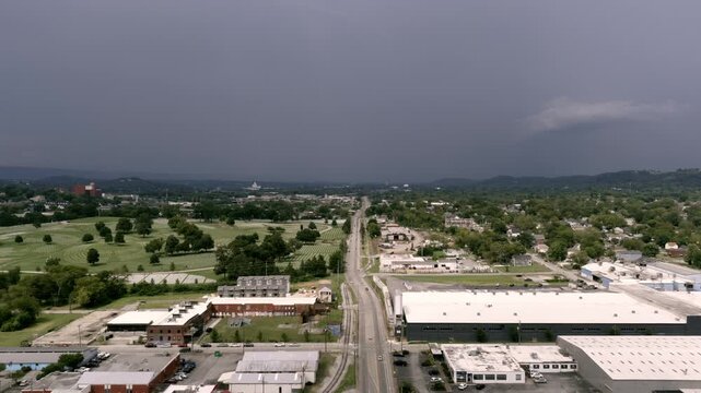 Aerial drone hyperlapse over Chattanooga, Tennessee, showing a straight road cutting through industrial buildings and neighborhoods under storm clouds.