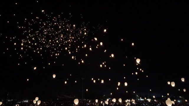Crowd releases glowing lanterns into the night sky at a winter festival in Cromwell