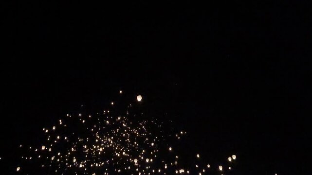 Crowd releases glowing lanterns into the night sky at a winter festival outdoors