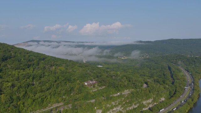 Drone shot of a misty mountain ridge above the Tennessee River near Chattanooga, with a curving highway hugging the shoreline.