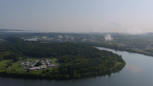 Drone shot of the Tennessee River curving past a wooded peninsula near Chattanooga, with industrial haze on the horizon.