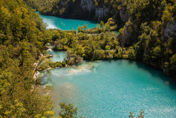 High angle aerial view of turquoise lakes, cascades and wooden boardwalk trails surrounded by lush forest in Plitvice Lakes National Park, Croatia. © michaldziedziak