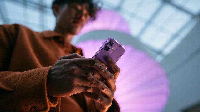 Young Man Texting and Browsing on Smartphone Indoors