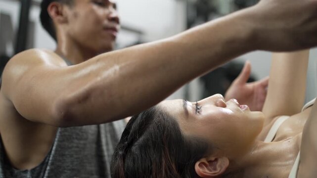 Fitness Instructor Guides Woman Through Dumbbell Press At Gym