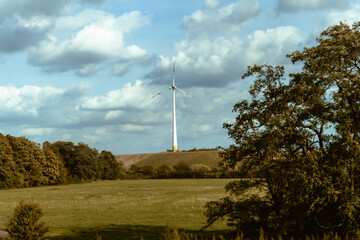 Obraz premium Wind turbine in green agricultural landscape under dramatic cloudy sky