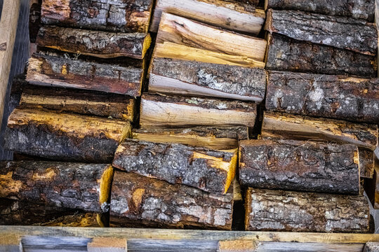 View of stacked firewood logs with rough bark and textured wood grain in Latvia.