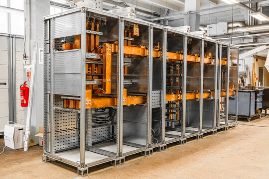 View of an industrial electrical switchgear cabinet with copper busbars and metal frame in a factory setting in Latvia.