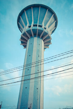 A towering concrete water tower set against a vibrant blue sky.
