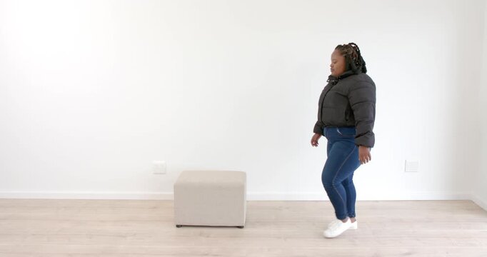 African American woman sitting on box indoors, looking forward with calm expression