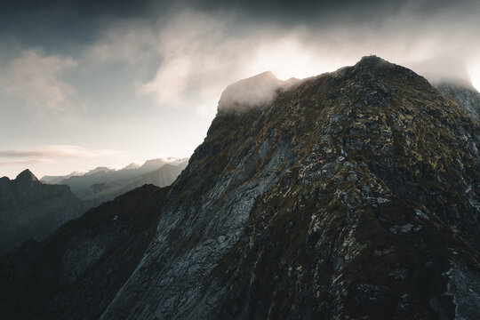 View of the rugged mountain ridge of Reinebringen with dramatic clouds and rocky slopes in Moskenes, Nordland, Norway.